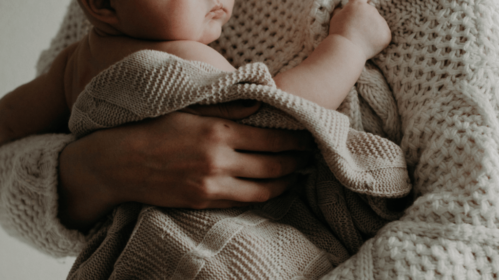 Baby wrapped in blankets being cuddled by a parent