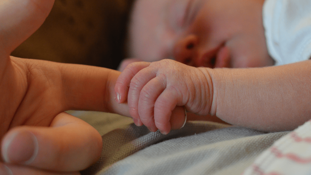 Small baby holding parents finger